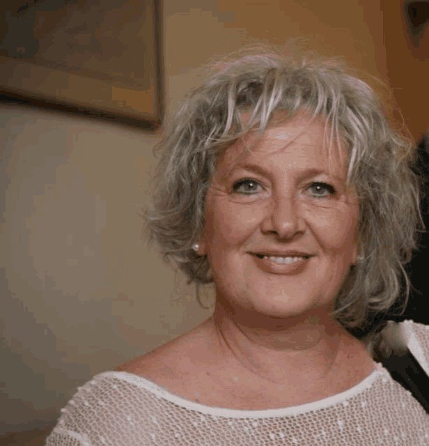 a woman with gray hair is smiling and wearing earrings