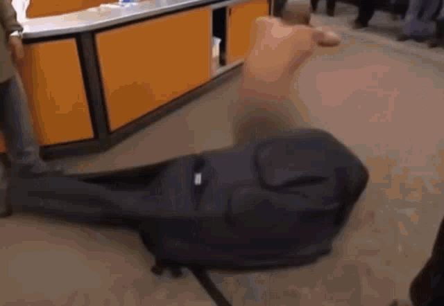 a man without a shirt is laying on the floor next to a large black bag .