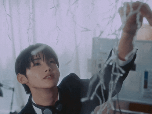 a young man in a tuxedo is playing with a string of christmas lights