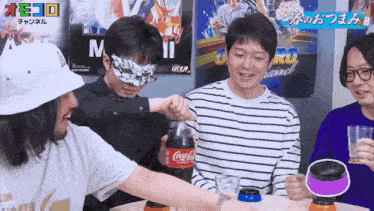 a group of people are playing a game with a coca cola bottle in the foreground