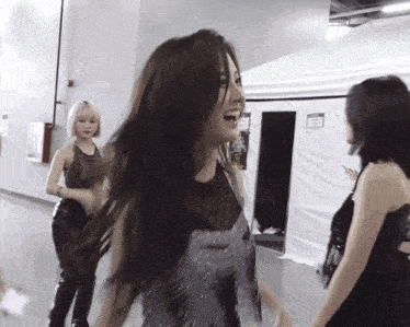 three women are standing in a room with a sign on the wall that says ' emergency exit '