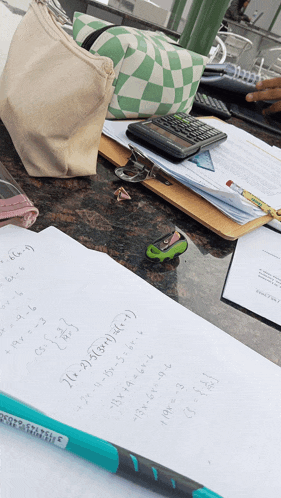 a green and white checkered bag sits on a table next to a calculator and some papers