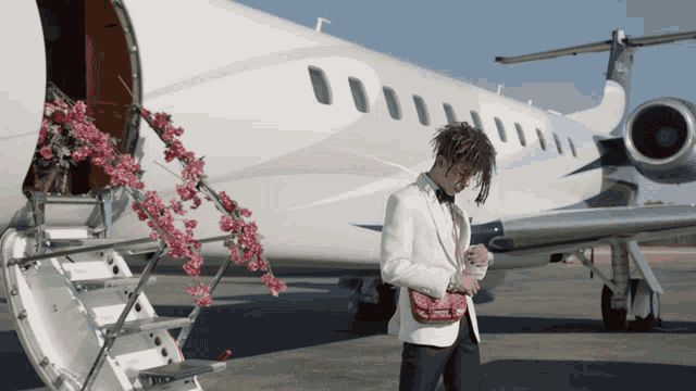 a man in a suit is standing in front of an airplane with flowers in the background
