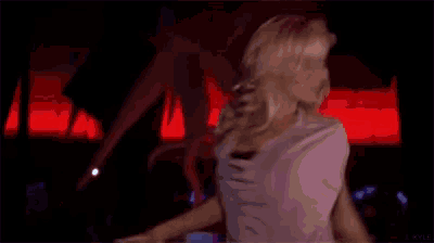 a woman in a red shirt is talking to a man in a pink shirt in a dark room .