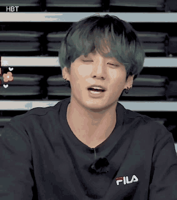 a young man with green hair is wearing a black fila sweatshirt