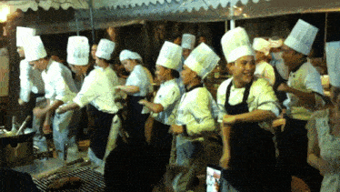 a group of people wearing chef hats and aprons are dancing in front of a sign that says ' thailand ' on it