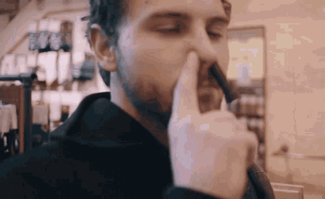 a man with a beard holds his finger to his nose