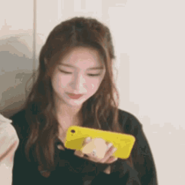 a woman is holding a yellow phone in her hand .