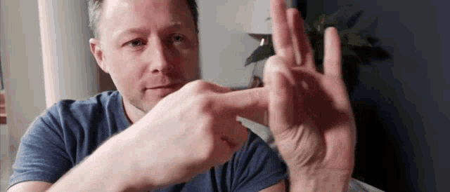 a man is making a peace sign with his hands while sitting on a couch .