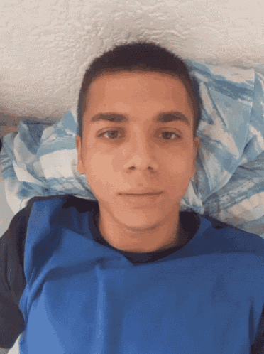a young man in a blue shirt is laying down