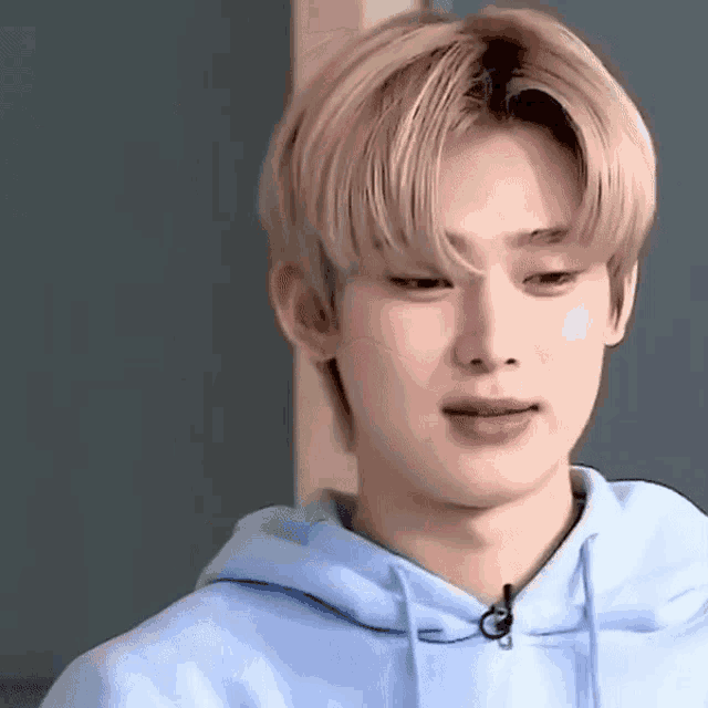 a close up of a young man wearing a blue hoodie and making a funny face .