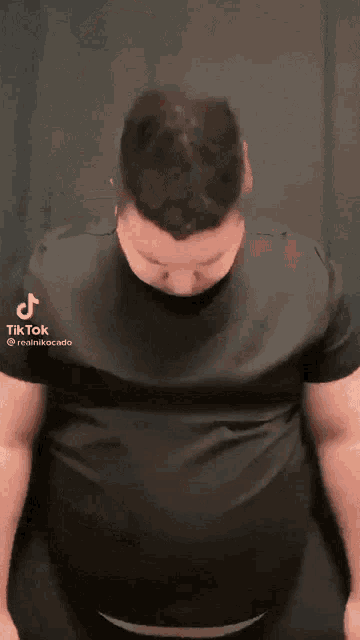 a man in a black shirt is standing in front of a curtain .