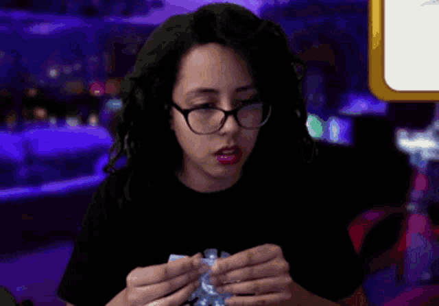 a woman wearing glasses and a black shirt is holding something