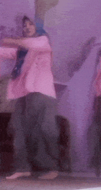 a woman in a pink jacket is dancing in front of a mirror .