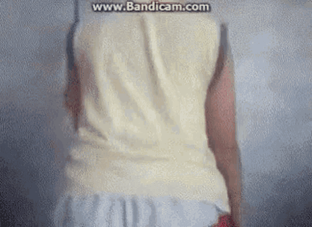a person wearing a white tank top and white shorts is standing in front of a wall .