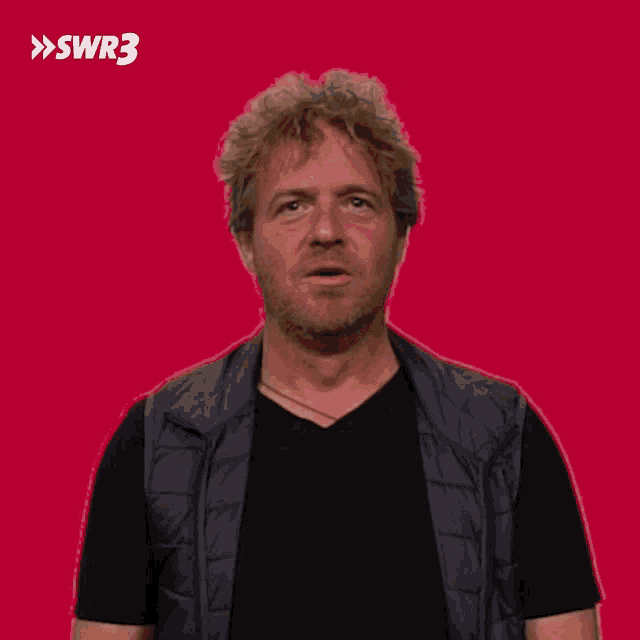 a man is making a funny face in front of a red background with the letters swr3 on it