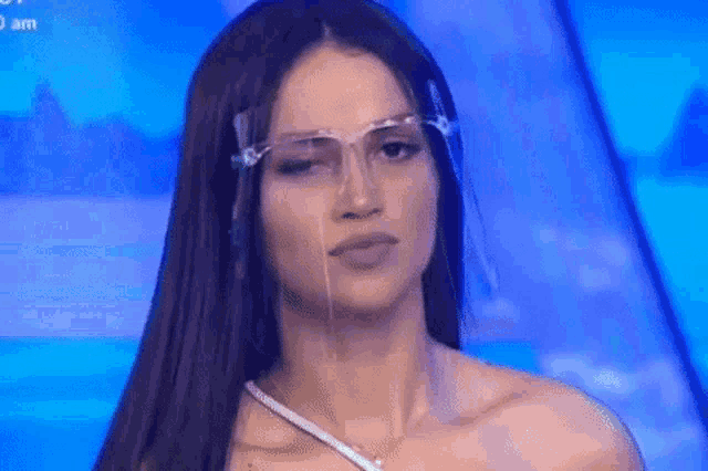a woman wearing a face shield and glasses is making a funny face .