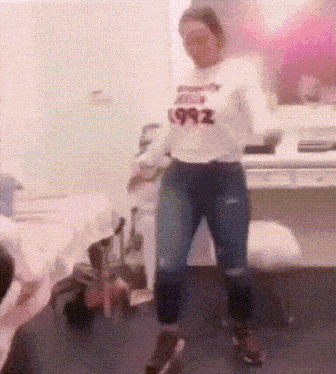 a woman is dancing in a room wearing a white sweatshirt that says 1992
