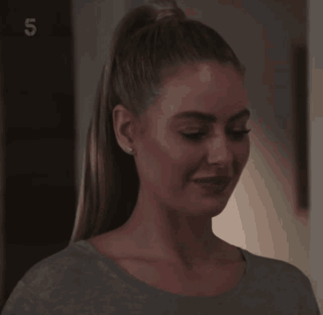 a woman in a ponytail is smiling in front of a sign that says 5