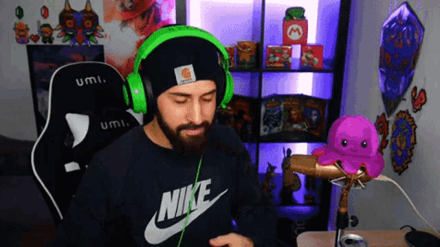 a man wearing headphones and a nike shirt stands in front of a microphone