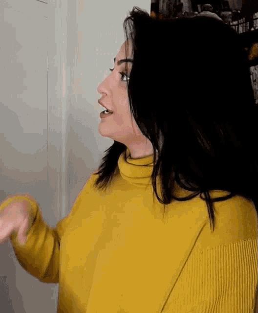 a woman in a yellow sweater is standing in front of a door .