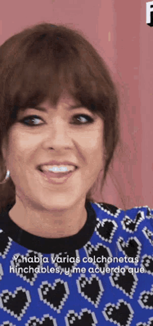 a woman in a blue sweater with hearts on it is smiling