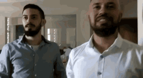 a man with a beard is standing next to another man in a room .