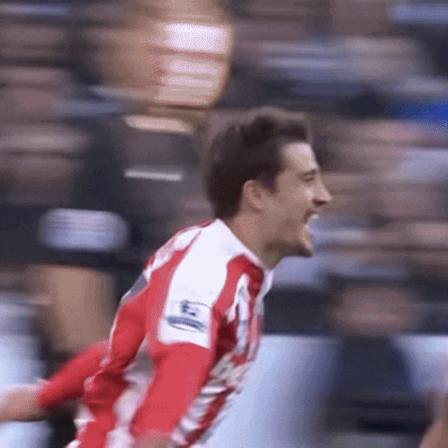a soccer player wearing a red and white jersey with the word barclays on his arm