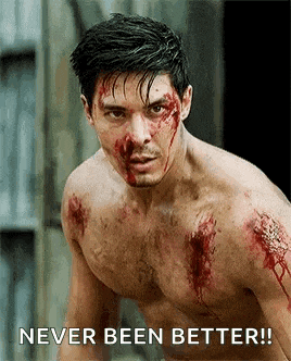 a shirtless man with blood on his face is standing in front of a building .