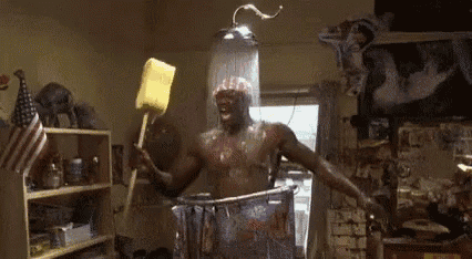 a man is taking a shower and holding a sponge in his hand .