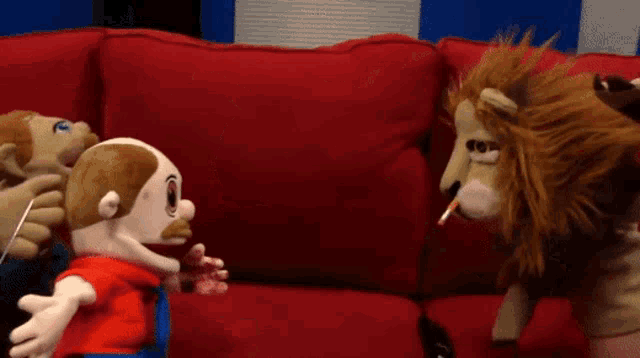 two stuffed animals are sitting on a red couch