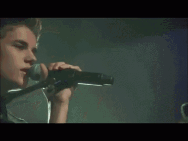 a man singing into a microphone with his hand on his chin