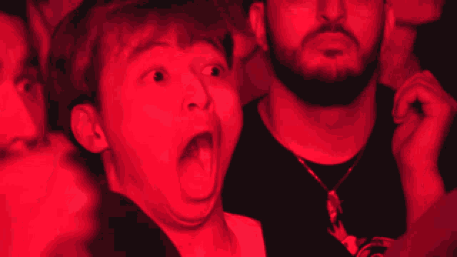 a man with a beard and a woman with their eyes closed are in a red light
