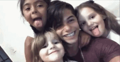a group of children are sticking their tongues out for a selfie .