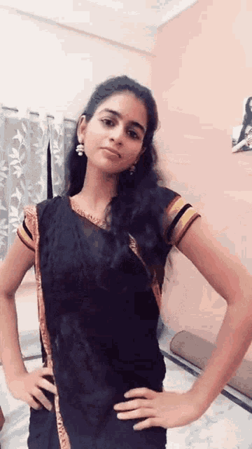 a woman with her hands on her hips is wearing a black top