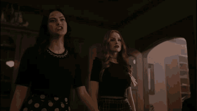 two women are standing next to each other in a dark room