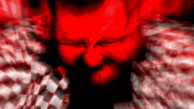 a man with a beard is wearing a plaid shirt and has a red background