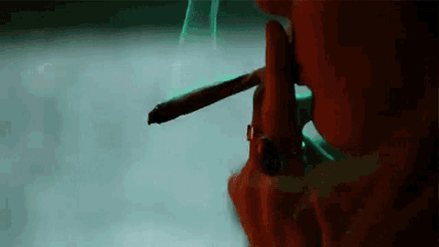 a person is smoking a cigarette in a dark room with smoke coming out of it .