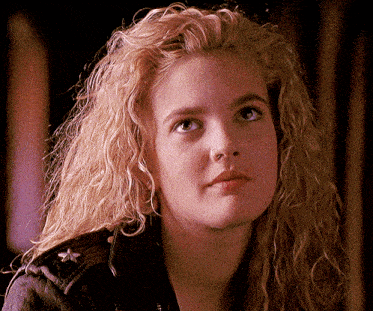 a woman with blonde curly hair wearing a black jacket
