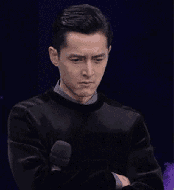 a man in a black sweater is holding a microphone .