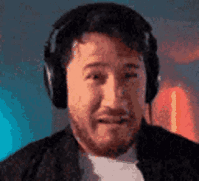a close up of a man wearing headphones and making a funny face .