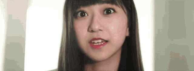 a close up of a woman 's face with long hair making a surprised face .