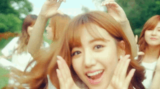 a group of girls are dancing in a park and one of them is making a funny face .