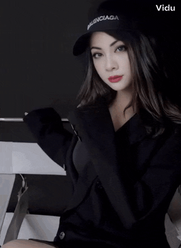 a woman wearing a black balenciaga hat and a black jacket