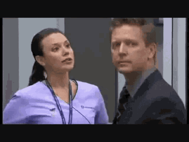 a man and a woman are standing next to each other in a room . the man is wearing a suit and tie .
