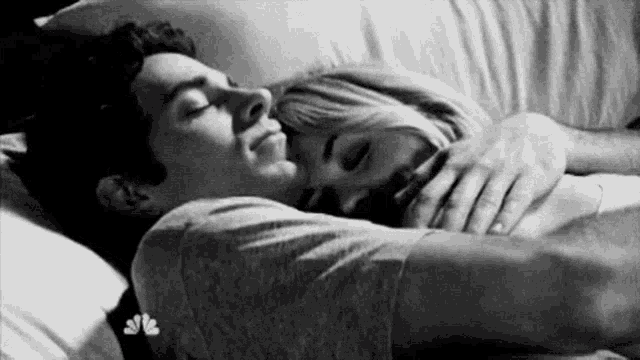 a black and white photo of a man and a woman sleeping in a bed .