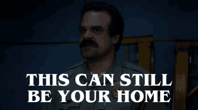 a man with a mustache is standing in front of a sign that says " this can still be your home "