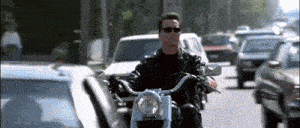 a man wearing sunglasses is riding a motorcycle on a busy street
