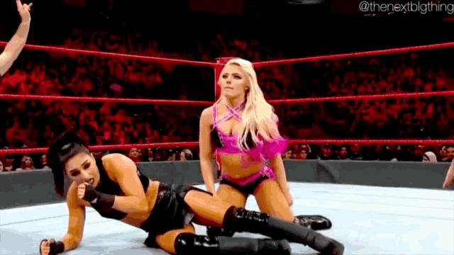 two women are wrestling in a wrestling ring with a crowd watching .