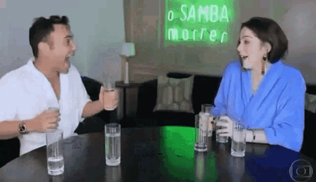 a man and a woman are sitting at a table with glasses of water